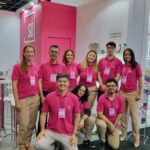 Equipe uniformizada com camisetas rosa em estande de evento empresarial
